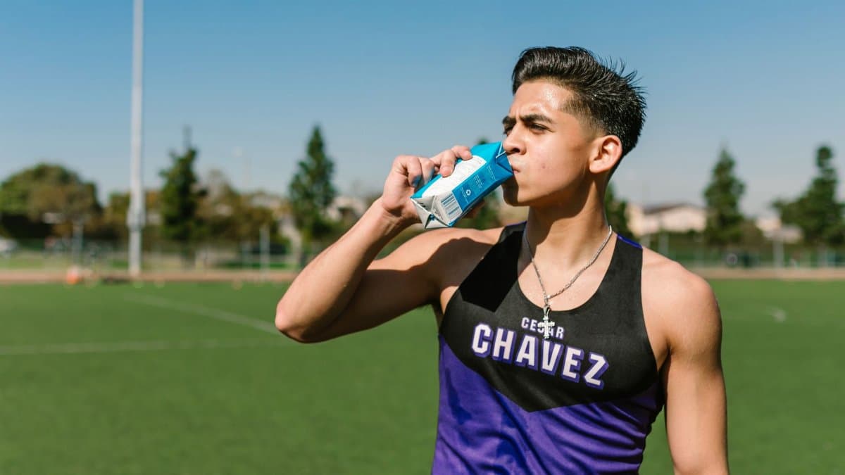 Teen athlete hydrating with a sports drink during an outdoor workout.