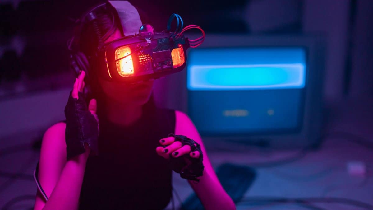 A woman immerses in virtual reality with neon-lit goggles and gloves in a tech-savvy environment.