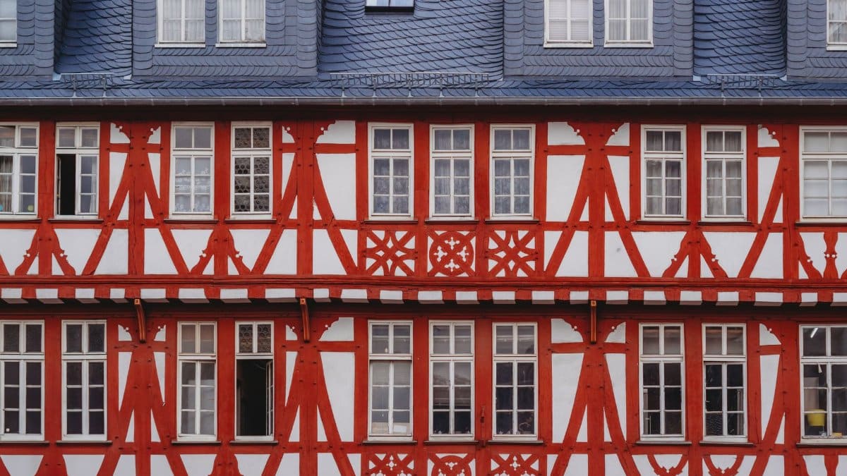 Close-up of a classic German half-timbered house exterior with red beams and white walls.