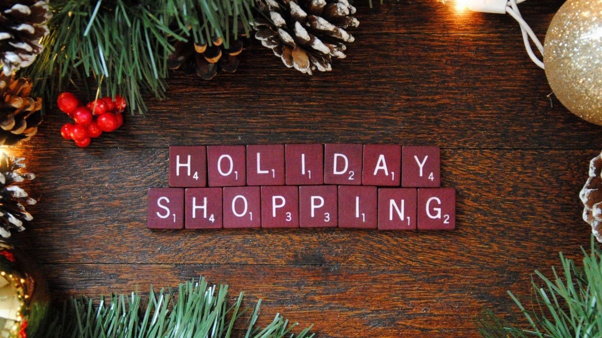 Top-down view of festive holiday shopping decoration with pine cones, berries, and lights.