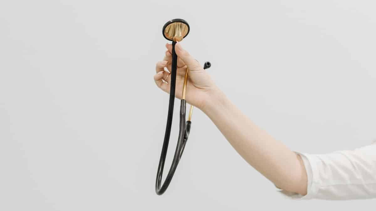 A hand holding a stethoscope, symbolizing medical care and healthcare on a white background.