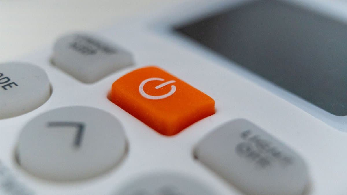 Detailed view of an orange power button on an electronic remote control device.
