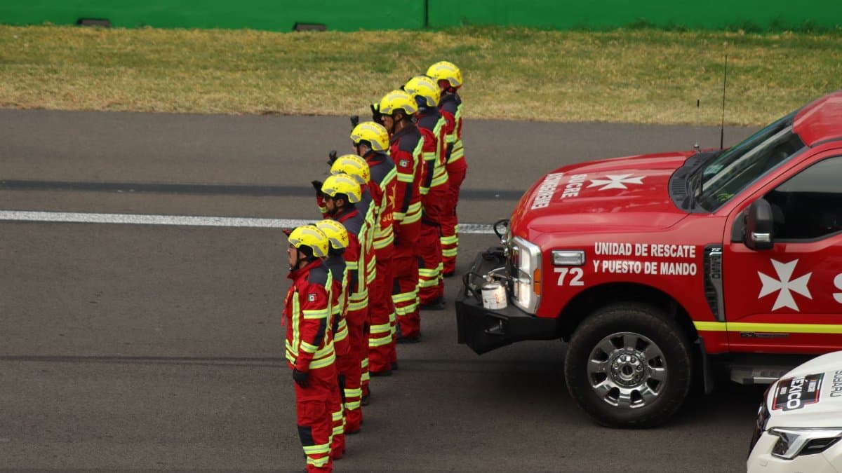 Rescue personnel in uniform lineup beside command vehicle in Mexico City.