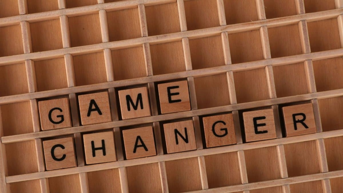 Scrabble tiles forming 'Game Changer' on a wooden grid, symbolizing innovation or transformation.