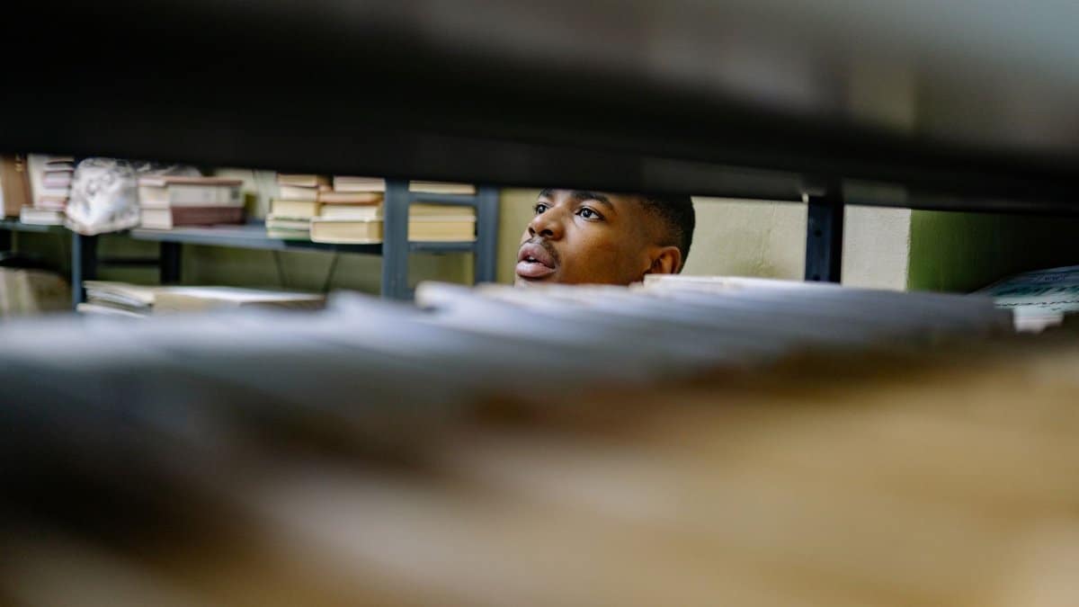 A man browsing through files in a library or archive, focused on tasks.