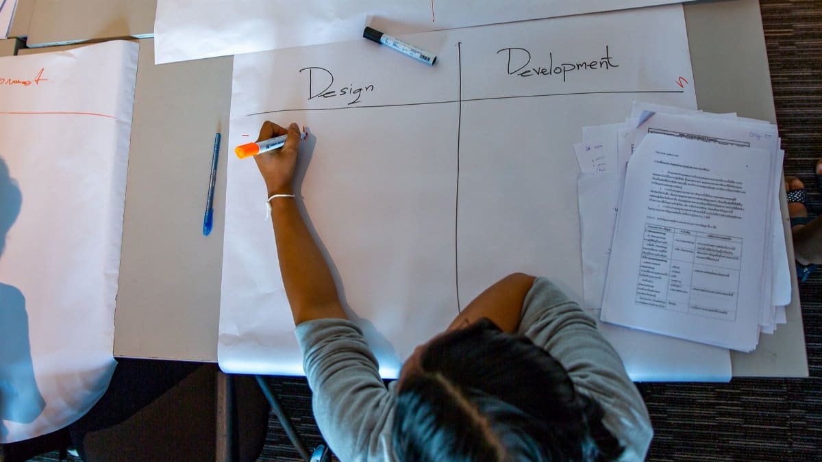 Woman engages in design and development planning at a desk with large papers and work documents.