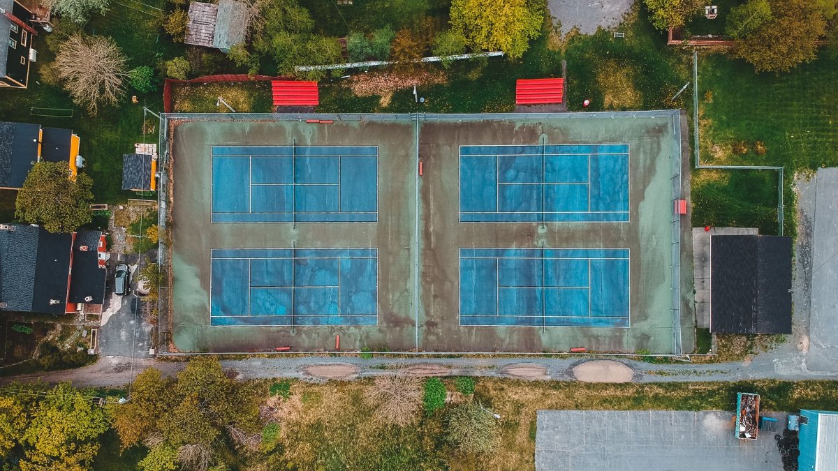 Modern tennis courts located amidst lush autumn trees and houses in calm town