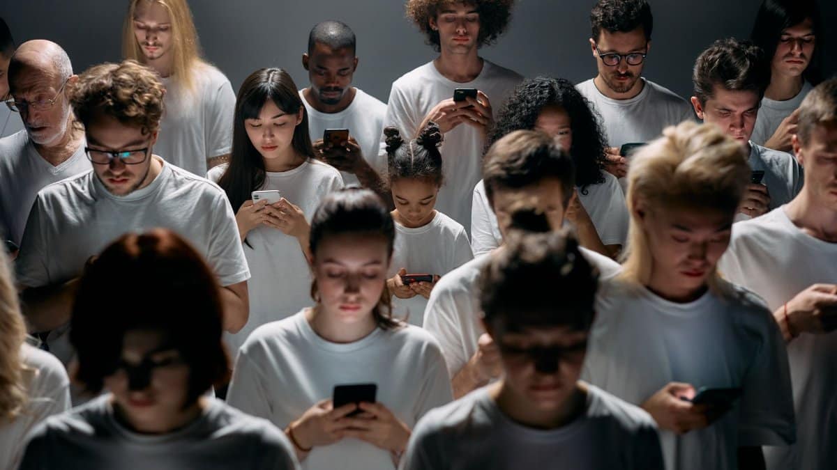 A diverse crowd of people using smartphones, highlighting modern social connections and isolation.