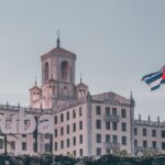 View of the historic Hotel Nacional in Havana, Cuba with a waving Cuban flag and clear sky.
