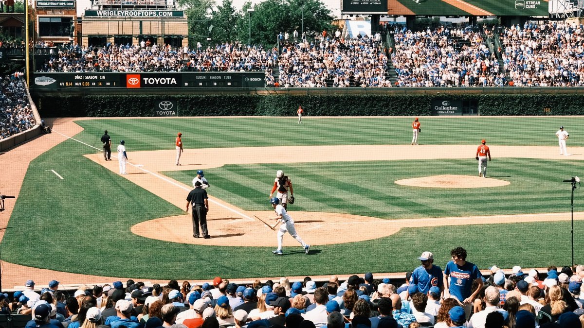 Vibrant scene of a baseball game at Wrigley Field with packed grandstands and players in action.