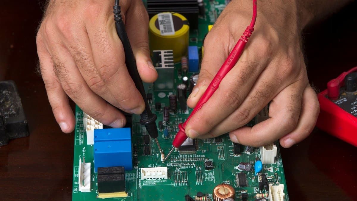 A detailed view of hands working on a circuit board using probes, depicting precision and electronics repair.