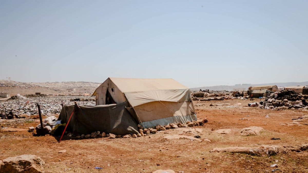 A solitary tent amidst rocky desert landscape in Idlib, Syria, illustrating life in arid conditions.