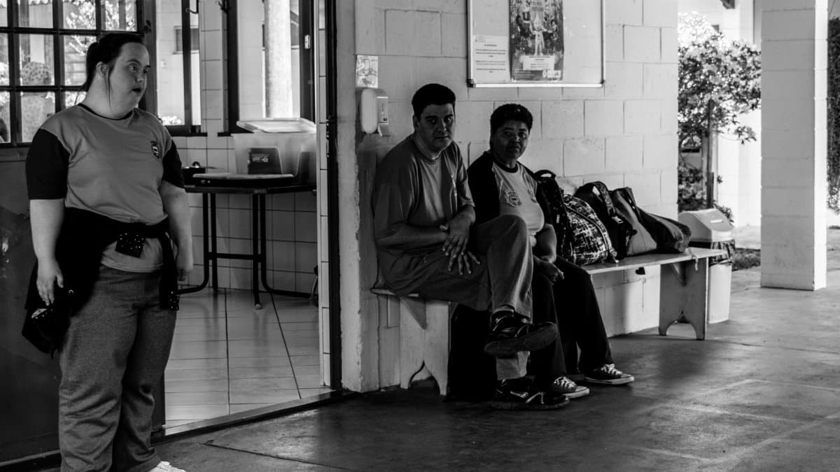 Three people sitting and standing in a community center in Jaguariúna, Brazil.