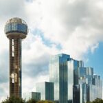 Reunion Tower and modern skyscrapers in Dallas, Texas against a cloudy sky.