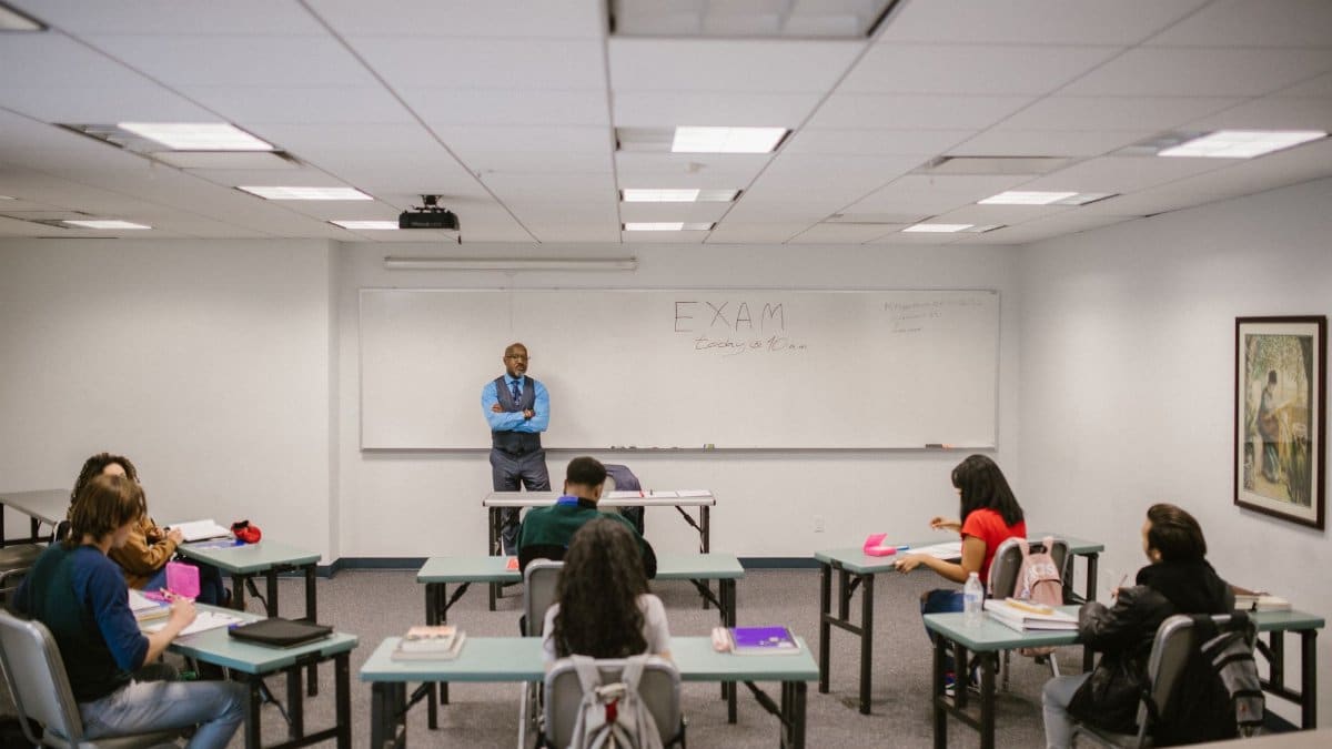 A classroom setting with a teacher proctoring an exam, students focused on their tests.