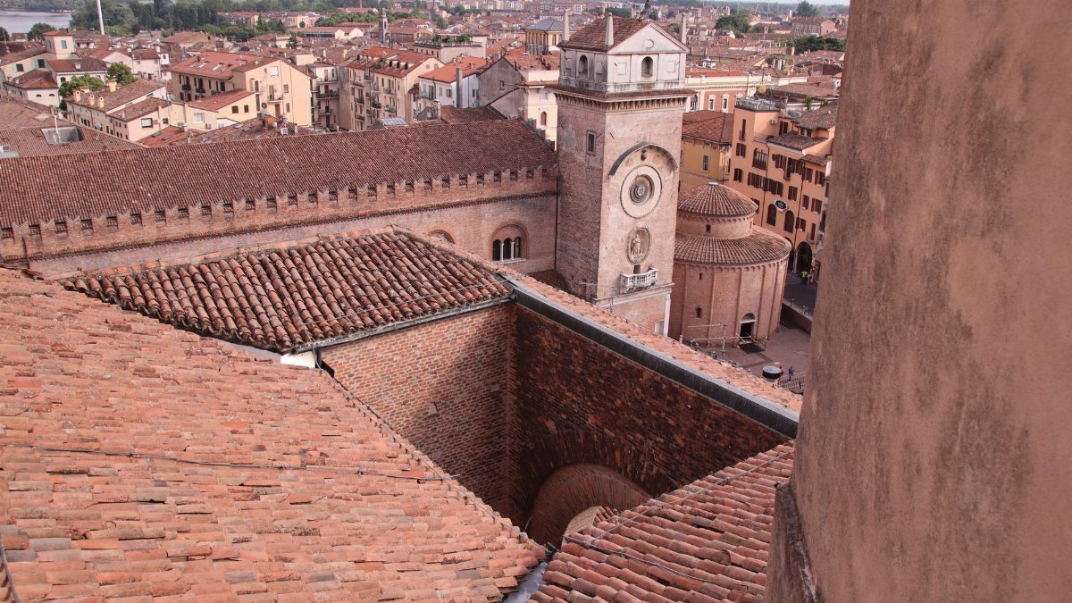 Aerial view of Mantua's historic architecture including a prominent clock tower and red-tiled roofs.