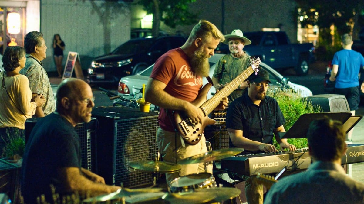 A vibrant street band performing live music at night, entertaining a small crowd outdoors.