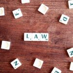Scrabble tiles spelling 'LAW' on a wooden table, symbolizing connections to education and legality.