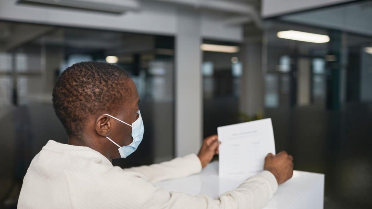 An individual wearing a face mask casts their vote in an indoor setting, representing voting during the pandemic.