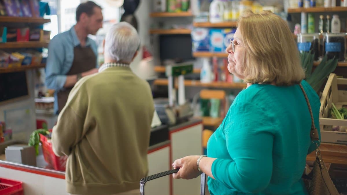 Senior woman with basket shopping in a cozy Portugal grocery store.