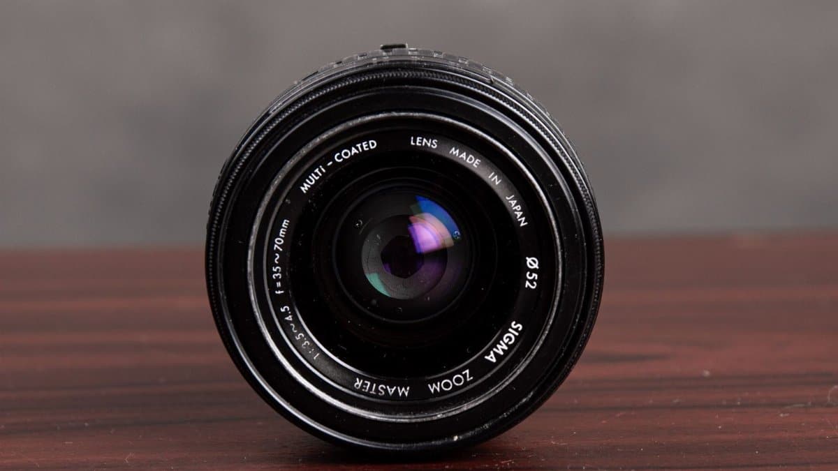 Detailed close-up of a Sigma Zoom lens on a wooden table showcasing lens details.