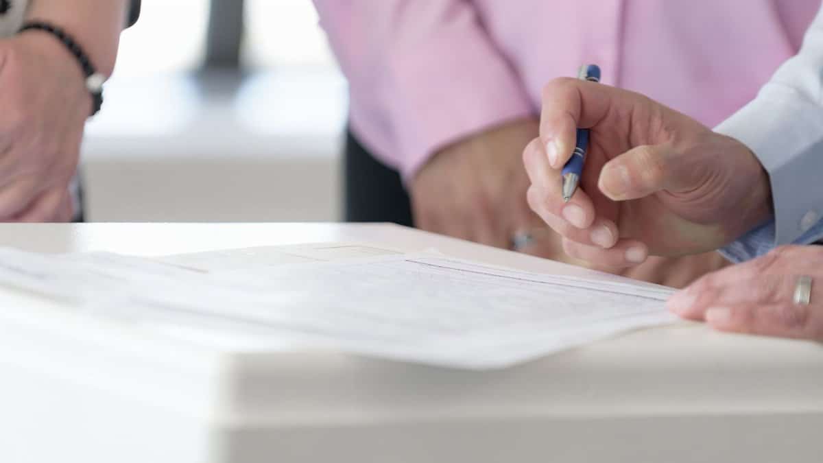 Close-up of hands signing documents in an office setting, emphasizing collaboration and decision-making.