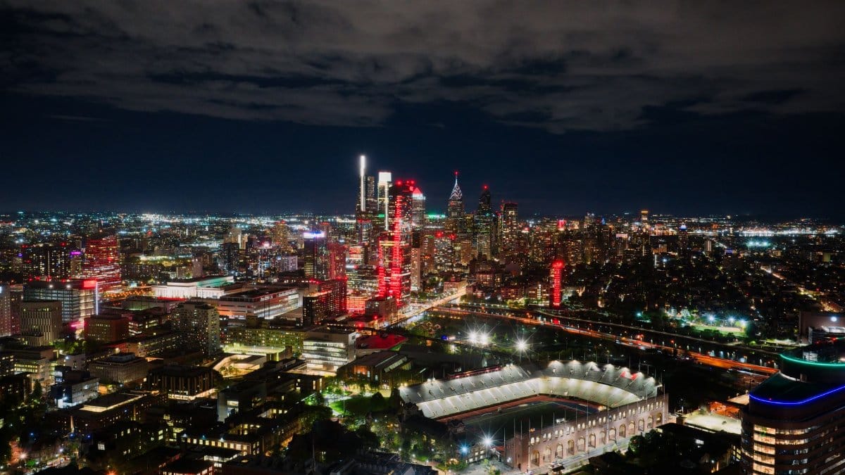 A breathtaking aerial view of Philadelphia's illuminated skyline at night, highlighting the vibrant cityscape and a prominent stadium.