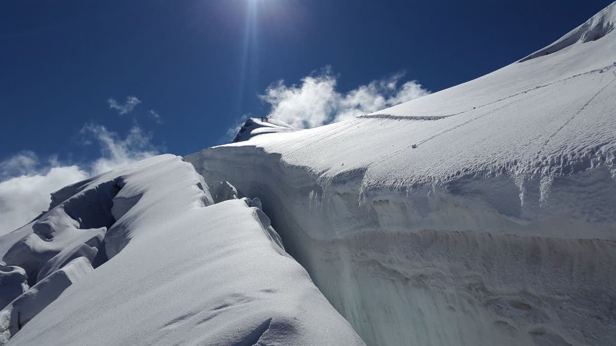A breathtaking view of a pristine alpine glacier under a clear blue sky with the sun shining brightly.