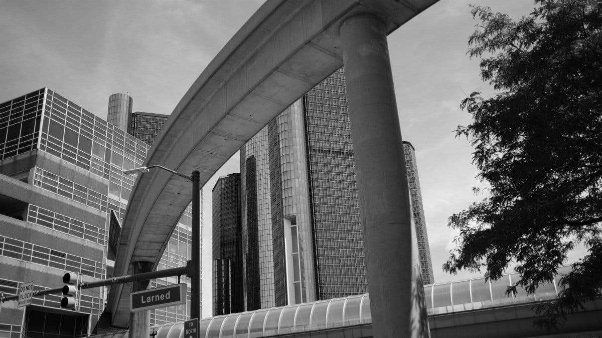 Monochrome view of a bridge overpass and city skyscrapers with trees.