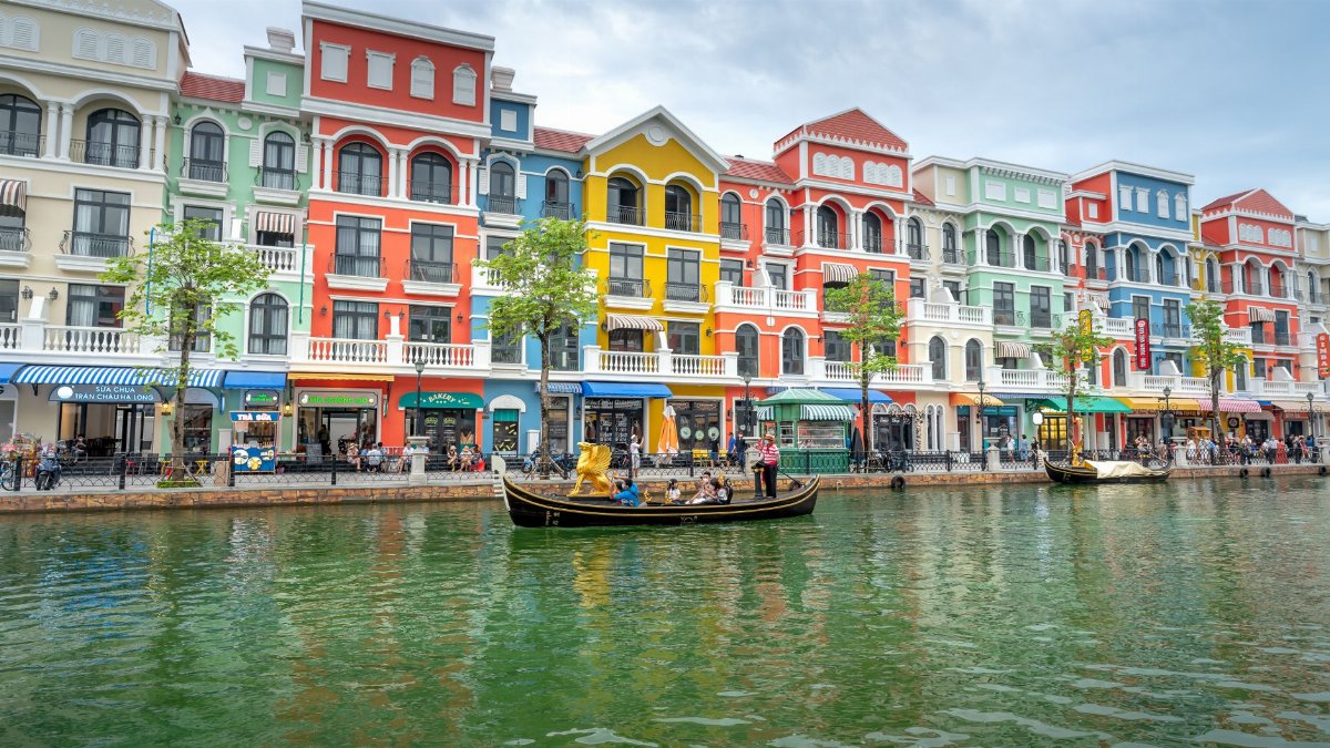 Vibrant facades line a canal with a gondola, capturing colorful urban scenery reminiscent of Venice.