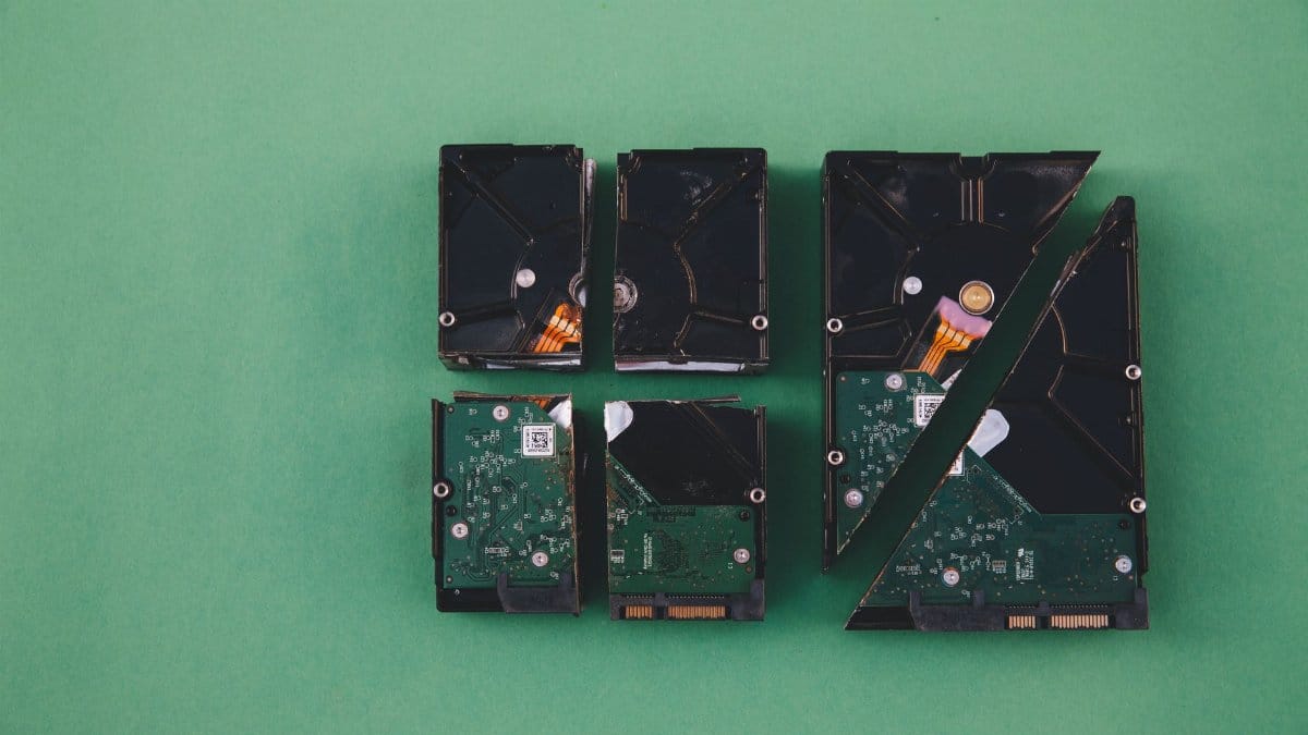 Four broken hard drives arranged on a green background, showcasing data destruction.
