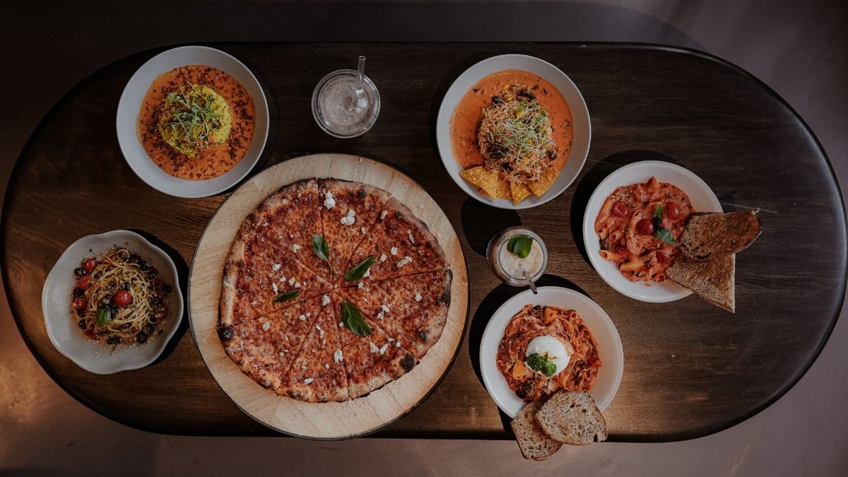 A variety of Italian dishes including pizza and pasta served on a wooden table.