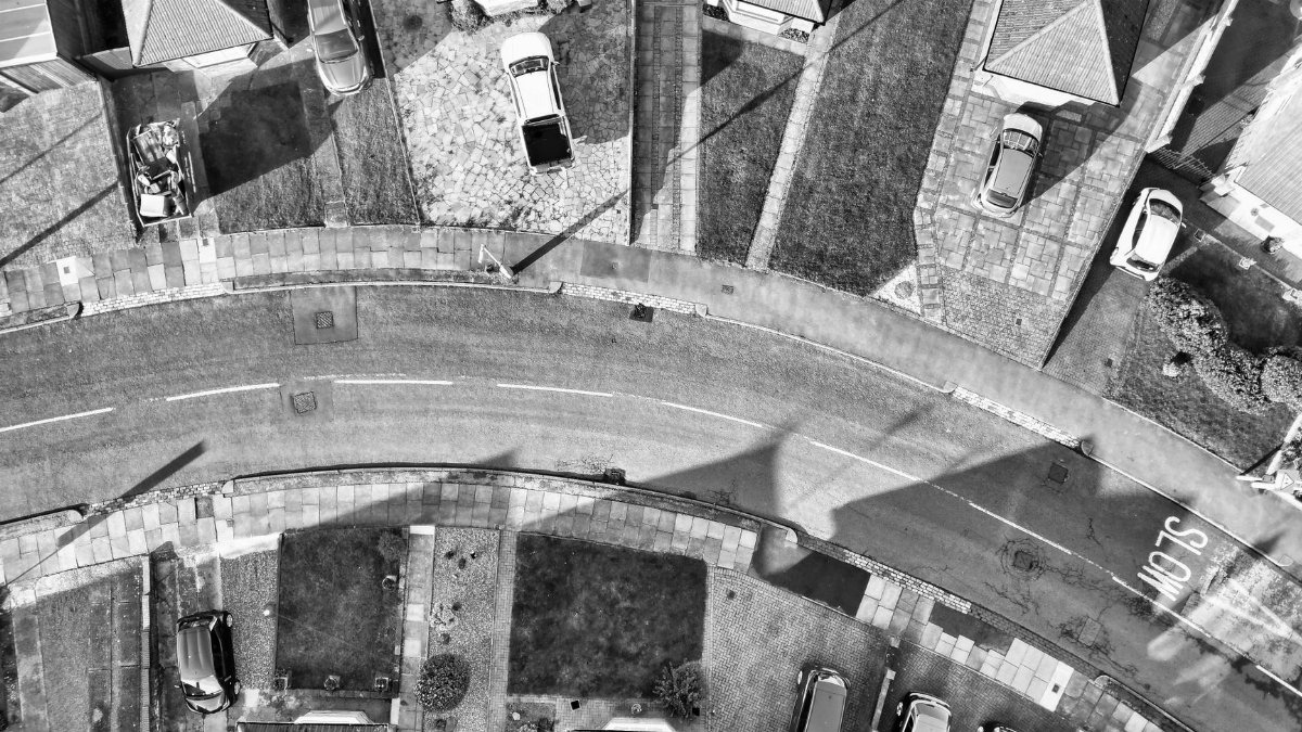 Black and white aerial view capturing a suburban neighborhood in Bedfordshire, England with parked cars and residential rooftops.