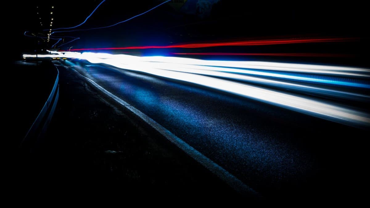 Long exposure shot of vibrant light trails on a highway at night, showing urban motion and speed.