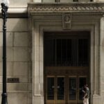 Exterior view of Chicago City Hall featuring intricate architecture and a lone pedestrian walking by.