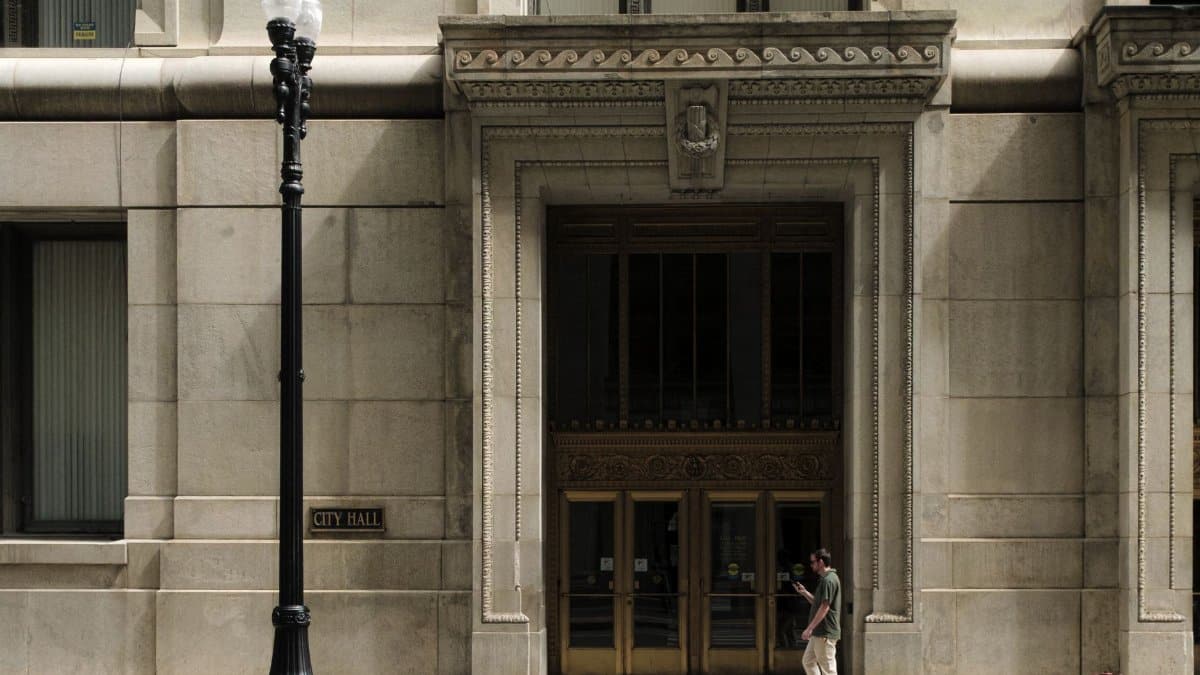 Exterior view of Chicago City Hall featuring intricate architecture and a lone pedestrian walking by.