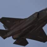 High-speed military jet flying through a clear blue sky at March Air Reserve Base.