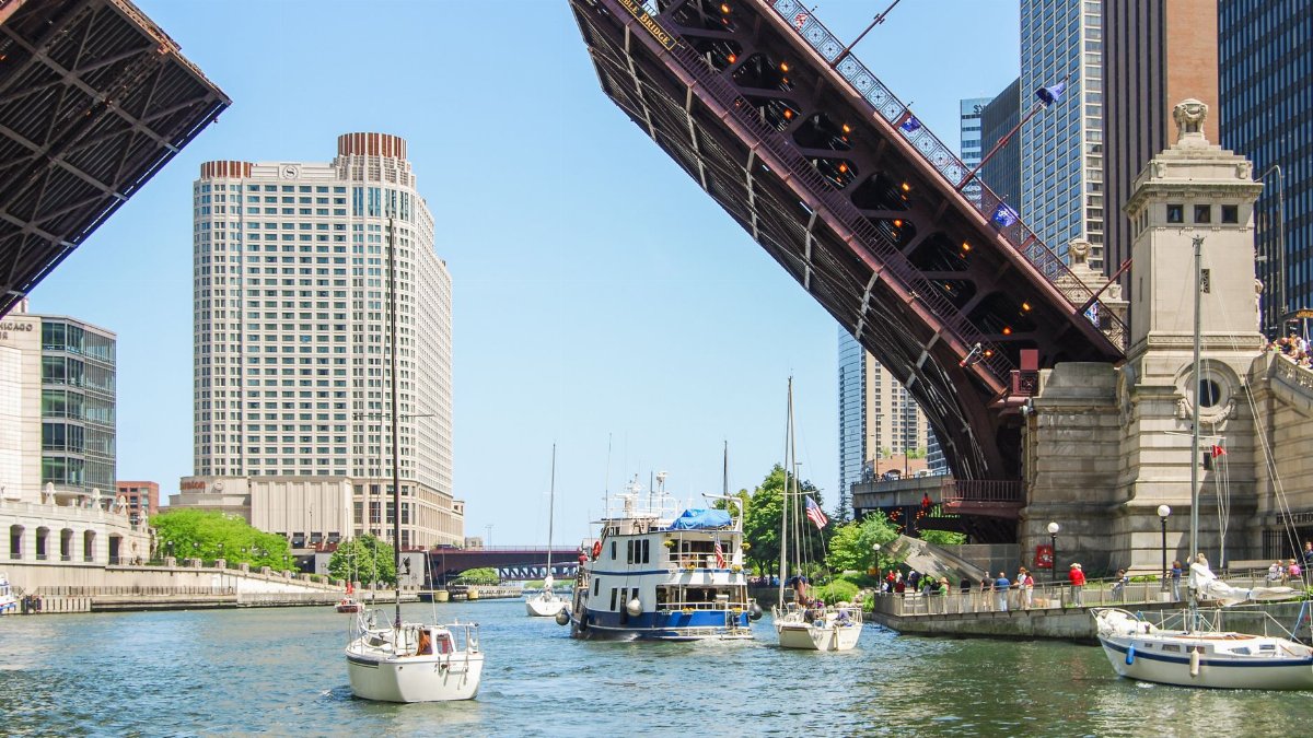 View of DuSable Bridge raised over the Chicago River with surrounding cityscape and boats.