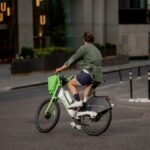 A man rides a Lime e-bike through a city street in London, embracing eco-friendly urban transport.