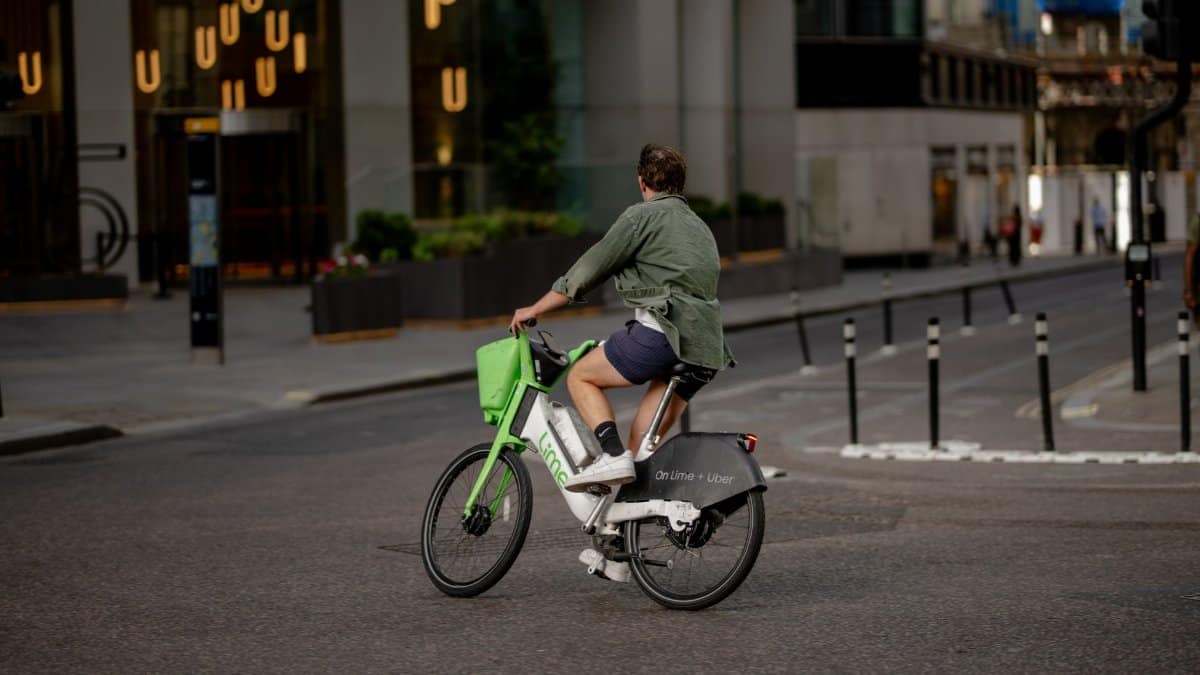 A man rides a Lime e-bike through a city street in London, embracing eco-friendly urban transport.