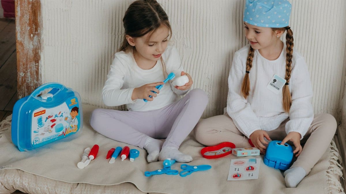Two young girls playing doctor with a toy medical kit indoors, fostering creativity and imagination.