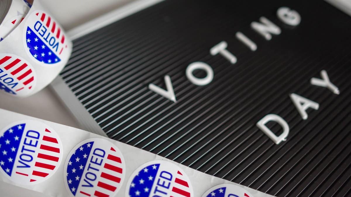 I Voted stickers with an American flag design and Voting Day sign symbolize U.S. electoral participation.