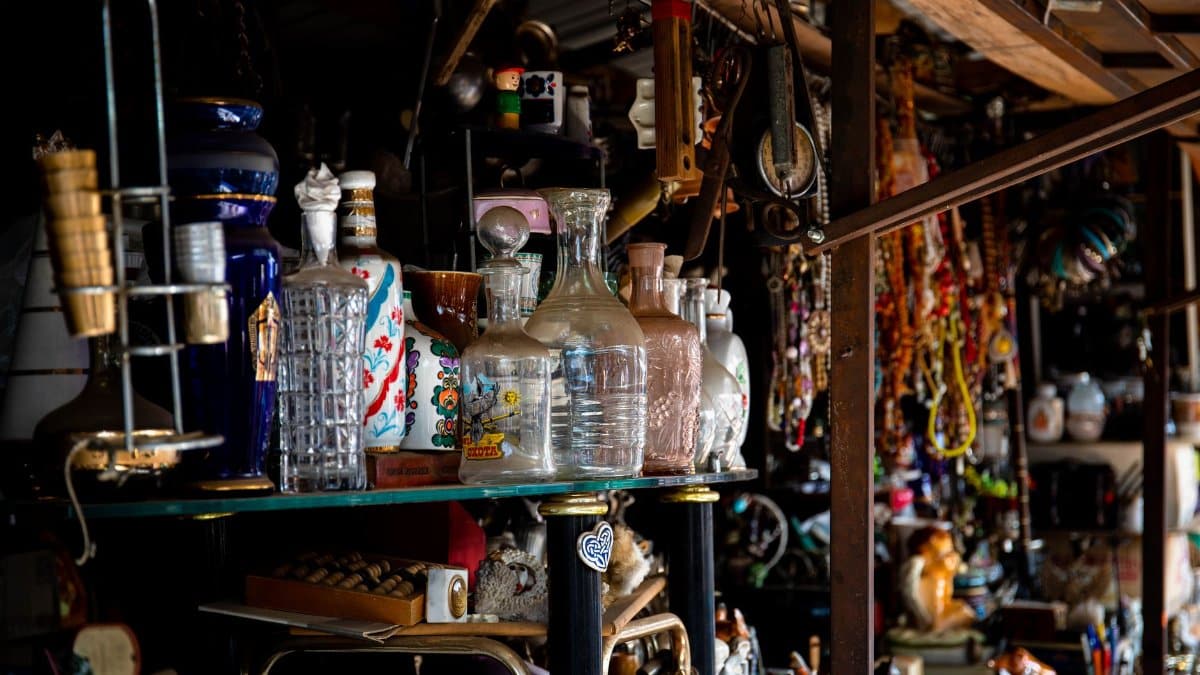 Eclectic assortment of vintage glassware and decor items displayed on a shelf in an antique store.