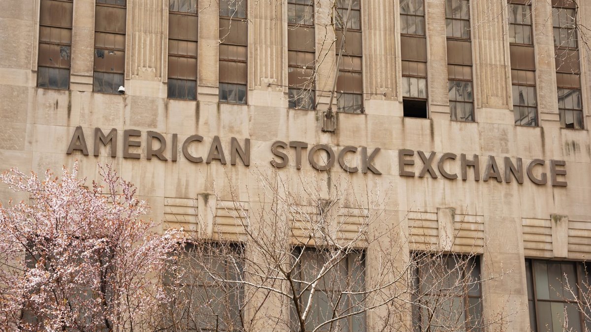 Facade of the American Stock Exchange Building in New York City during spring with blooming trees.