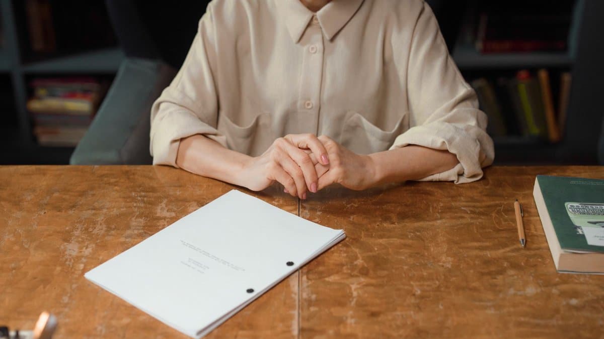 Woman sitting at wooden desk reviewing a screenplay in an office setting.