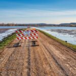 A road closed sign on a gravel path next to a flooded area in Kellogg, MN.
