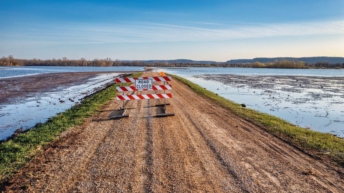 A road closed sign on a gravel path next to a flooded area in Kellogg, MN.