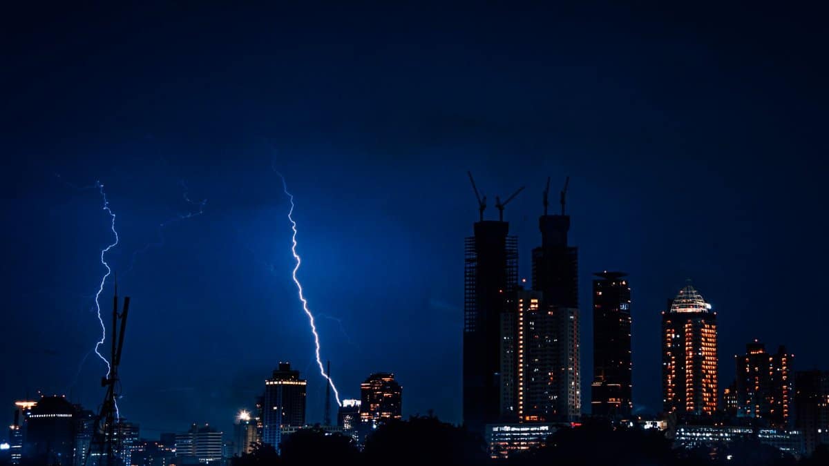 Dramatic view of Jakarta's skyline illuminated by lightning during a night storm.