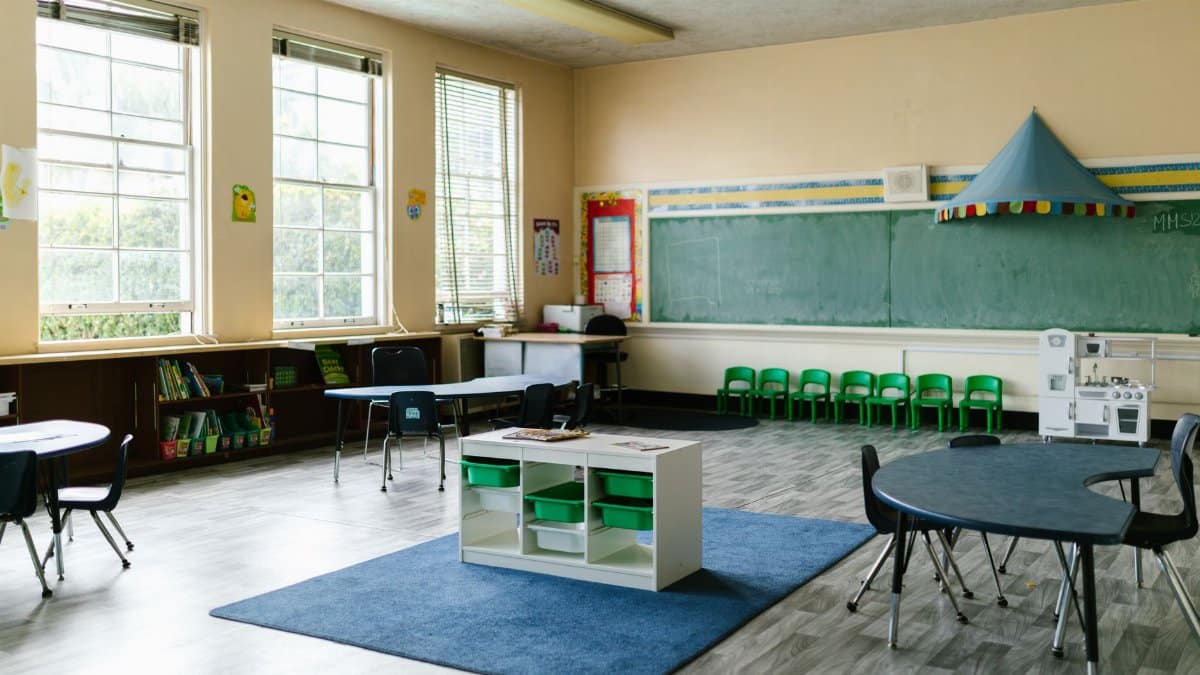 Spacious preschool classroom interior with tables, chairs, and a chalkboard for a learning environment.