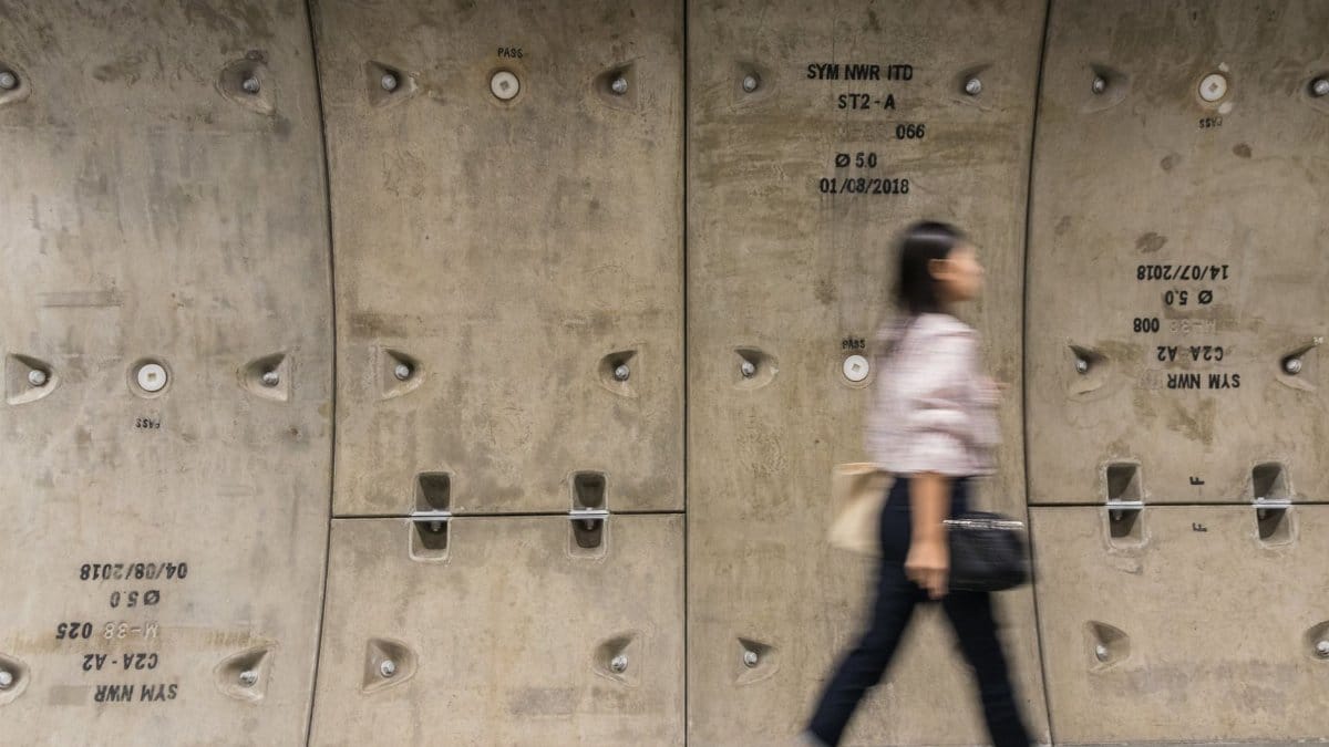 Blurred motion of a woman walking against an urban concrete wall. Urban life concept.